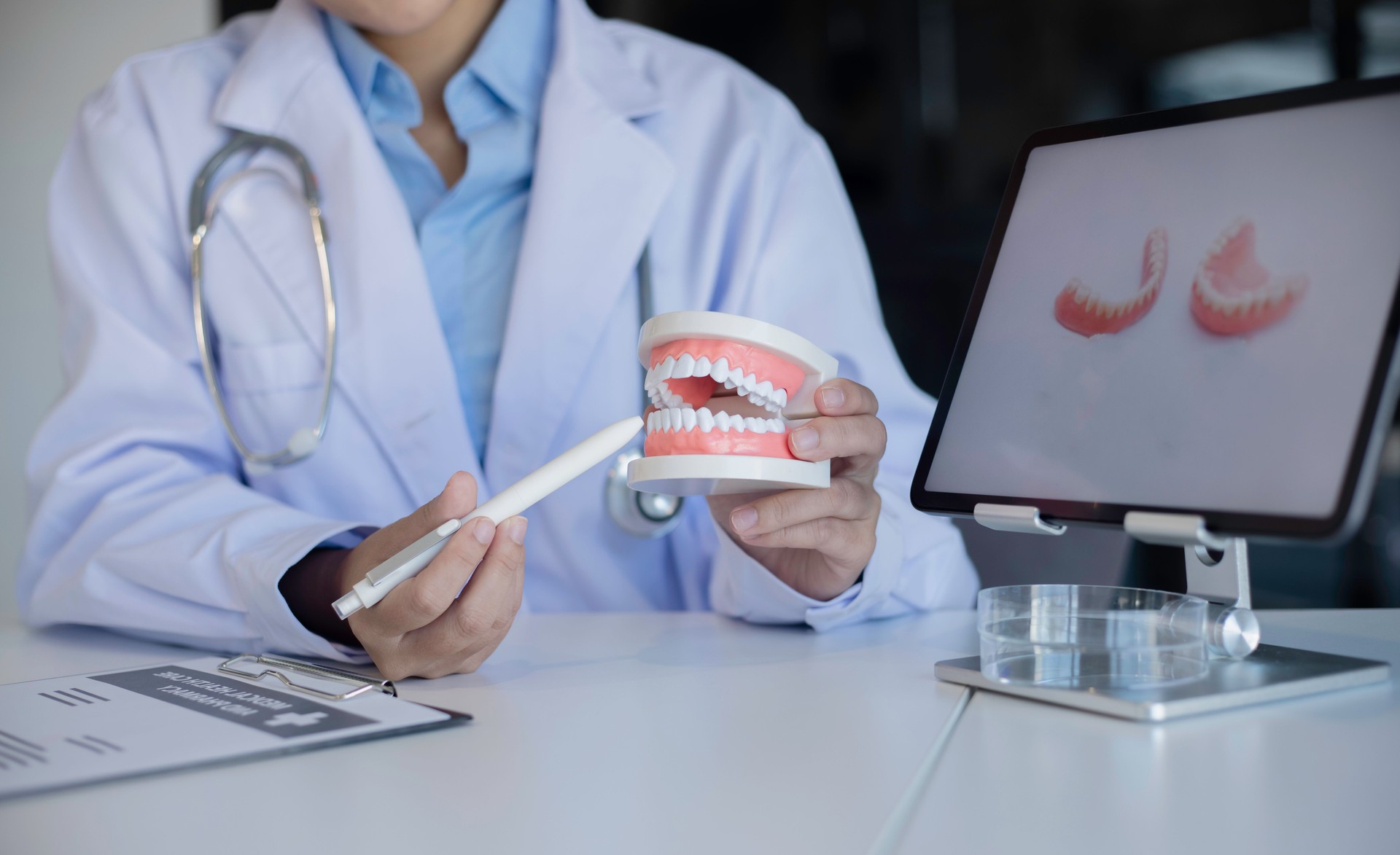 Dentist With Tooth Model At Dental Clinic.