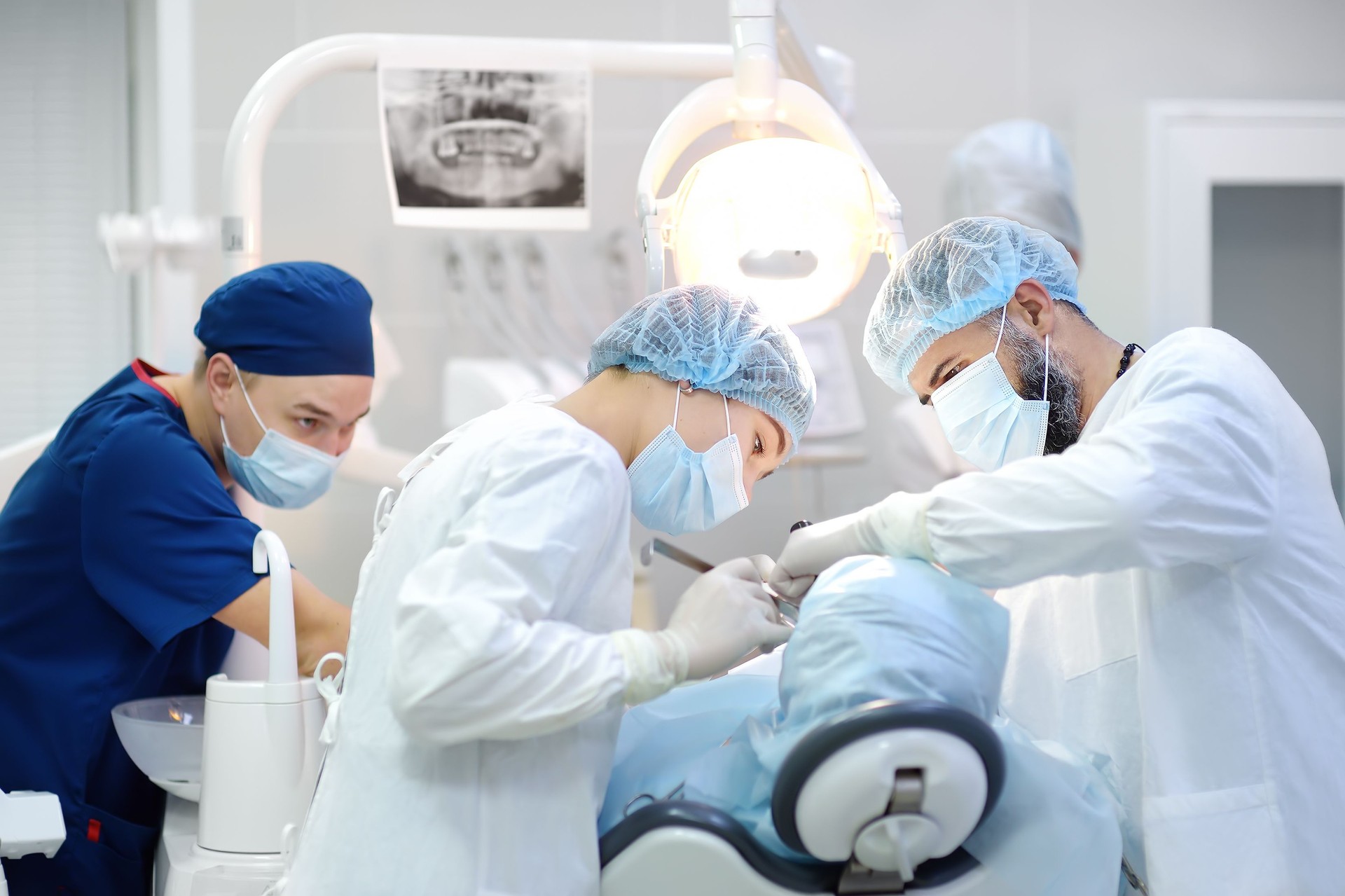 Surgeon and nurse during a dental operation. Anesthetized patient in the operating room. Installation of dental implants in the clinic.